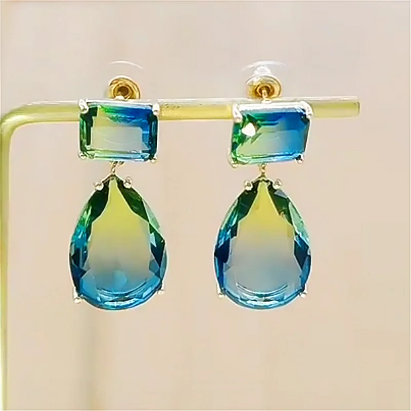 Beautiful Greenblue coloured crystal earrings in a drop dangle style with a stud and butterfly type backing. displayed on a jewellery stand