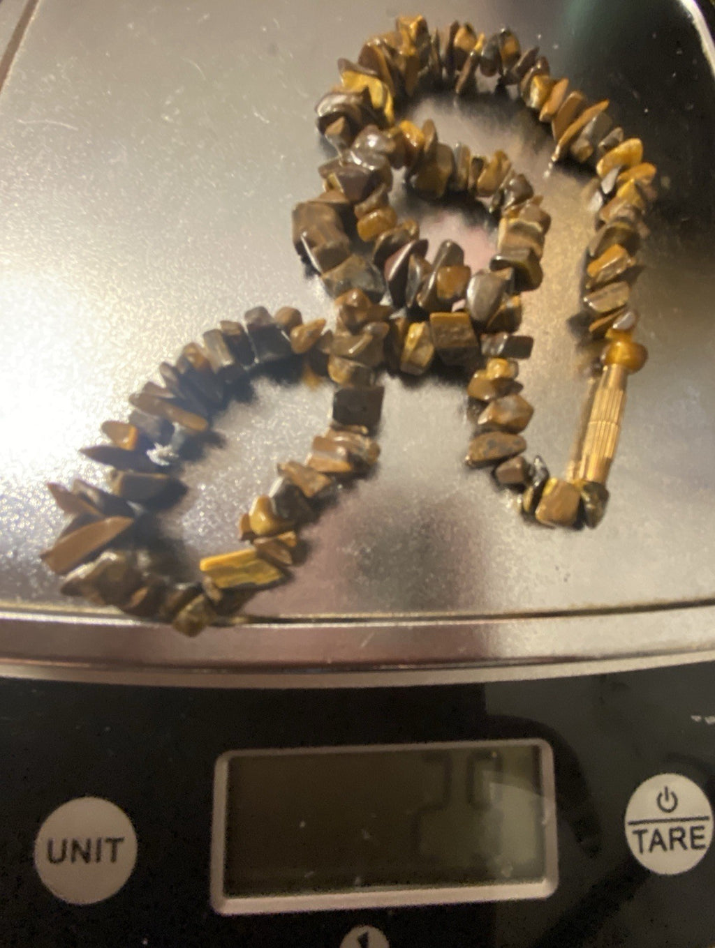 A beaded necklace made of polished tiger's eye stones, displayed on a digital scale showing a weight of 29g.
This is an unaltered image