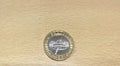 A 2016 British pound coin commerative of William Shakespear  resting on a light-colored wooden surface.