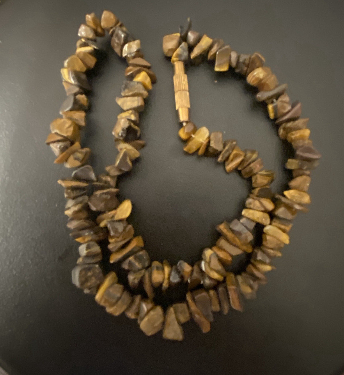 A handmade beaded necklace made of irregular, polished tiger's eye stone chips in shades of brown and yellow, displayed on a dark gray surface. This is an exact image of the necklace
Image 2 = real photo, clasp accurate ✅