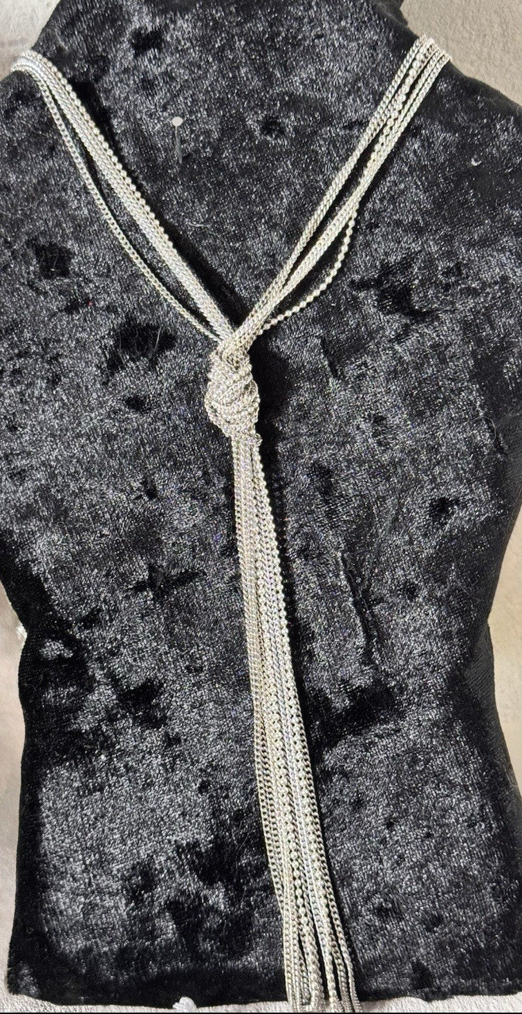 this s a silver toned metal necklace of several strands of ball beads tied in a central knot which can be adjusted so its a nice Y style lariat necklace in silver tone displayed on a black velvet style bust
