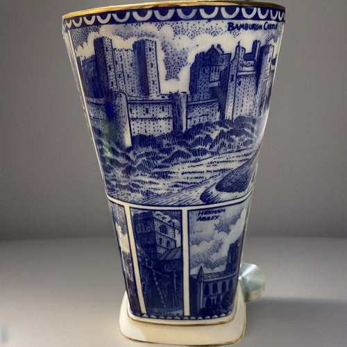A blue and white illustrated ceramic Vase, Ringtons Tea Collectibles, Landmark Vase with blue architectural cityscape panels and gold trim, photographed on a light gray studio background with a cast shadow.