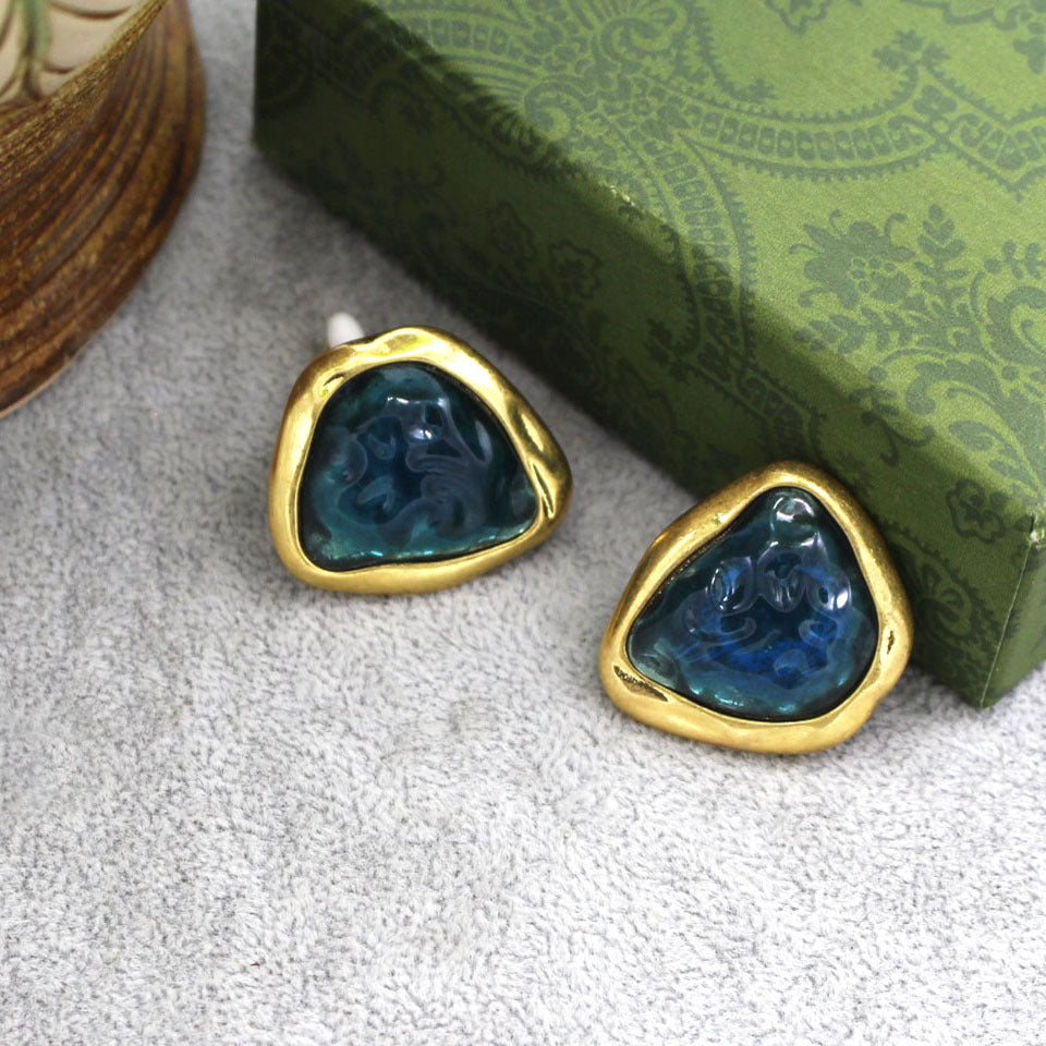 Another Angle Of the Abstract triangular pair of earrings with a sea blue/ green centre, set against A Mid Olive green Box