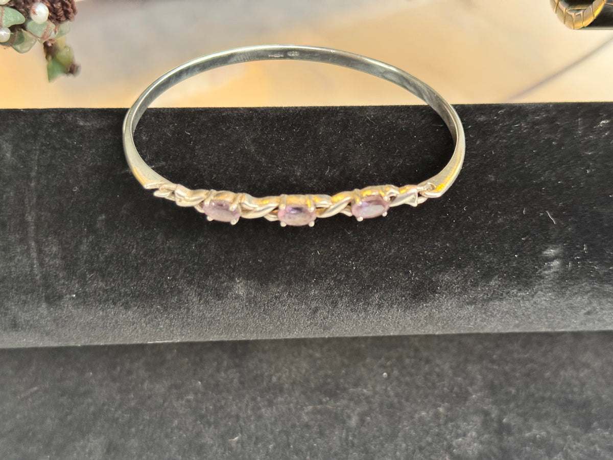 A beautiful original image of the sterling silver bracelet with Amethyst coloured stones. On top of a bracelet holder.
