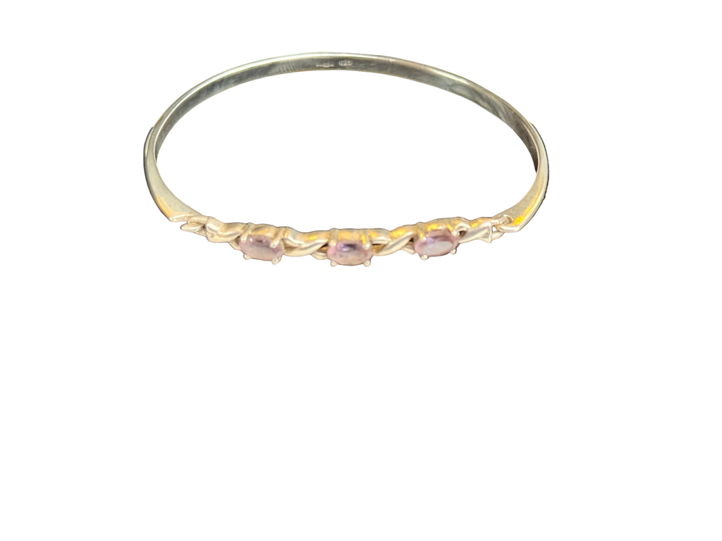 A Sterling Silver Hallmarked bangle bracelet featuring three small, oval-cut light pink gemstones set along the front band, photographed against a solid white background.