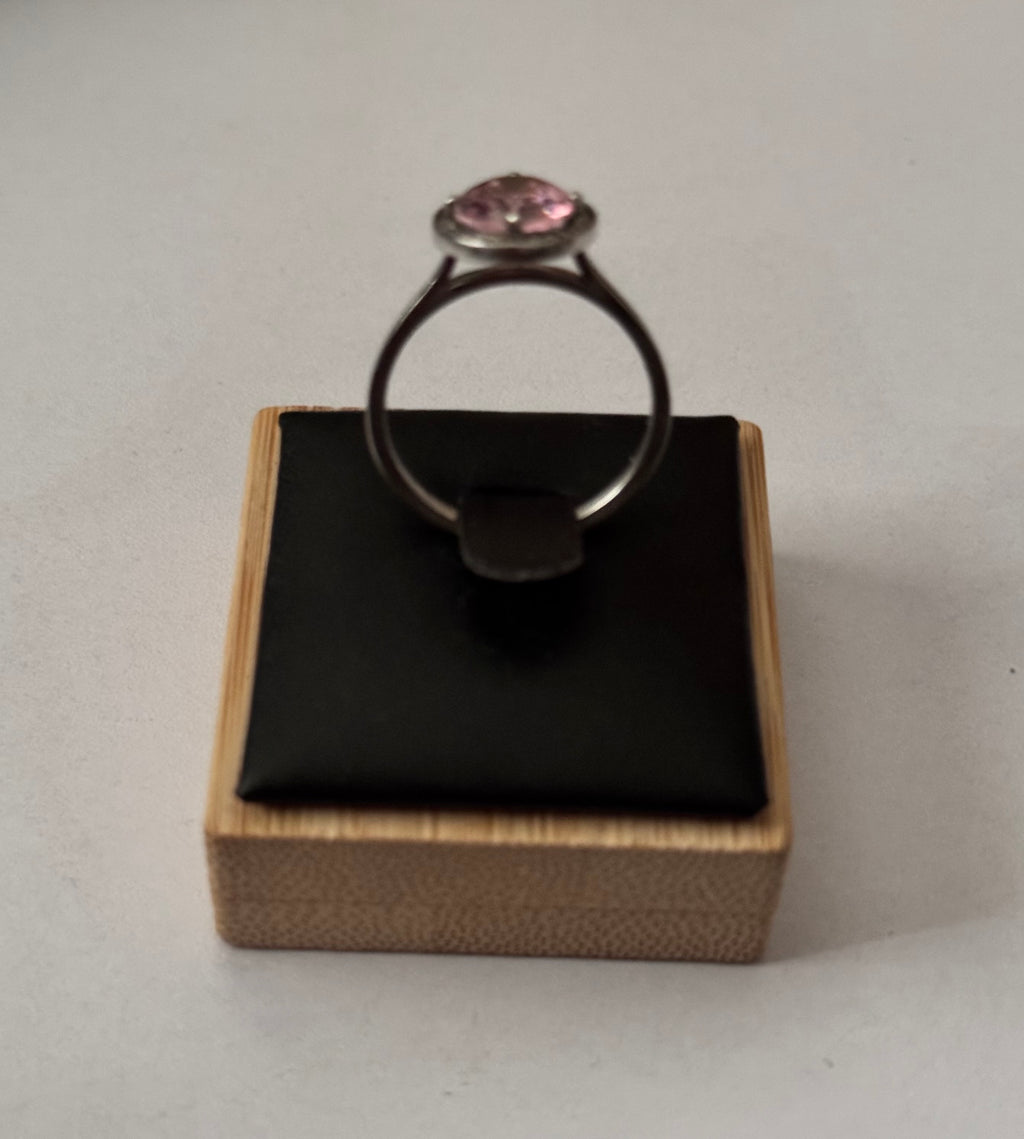A silver ring with an oval pink gemstone, displayed on a black cushioned wooden jewellery box against a light grey background. Vintage Azende Sterling Silver S925 Ring Pink Stone & Pavé