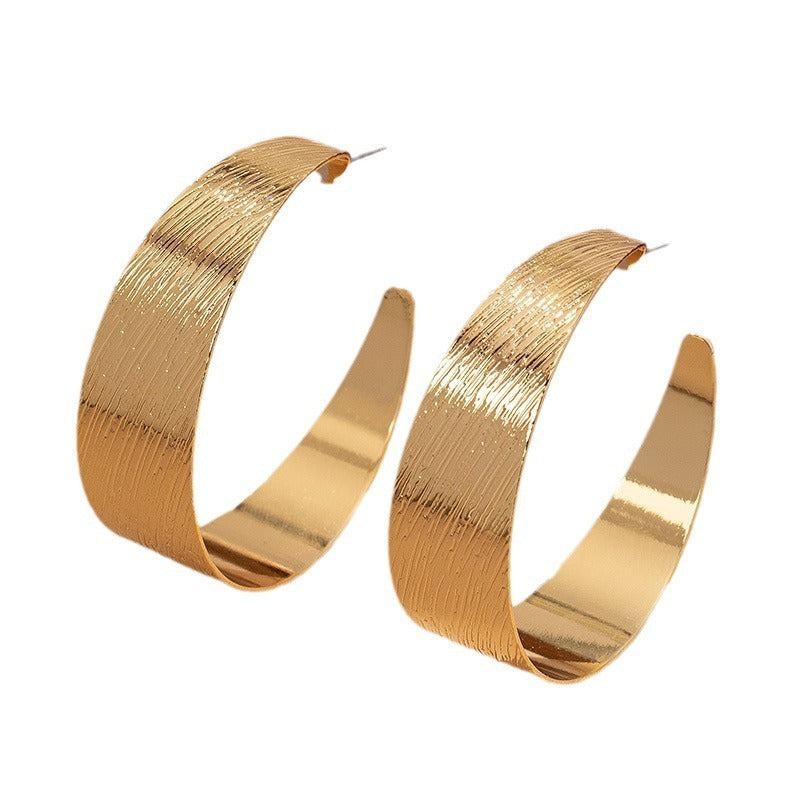 Textured Golden half hoop earrings 1 pair of the wider style 80s style on a white background