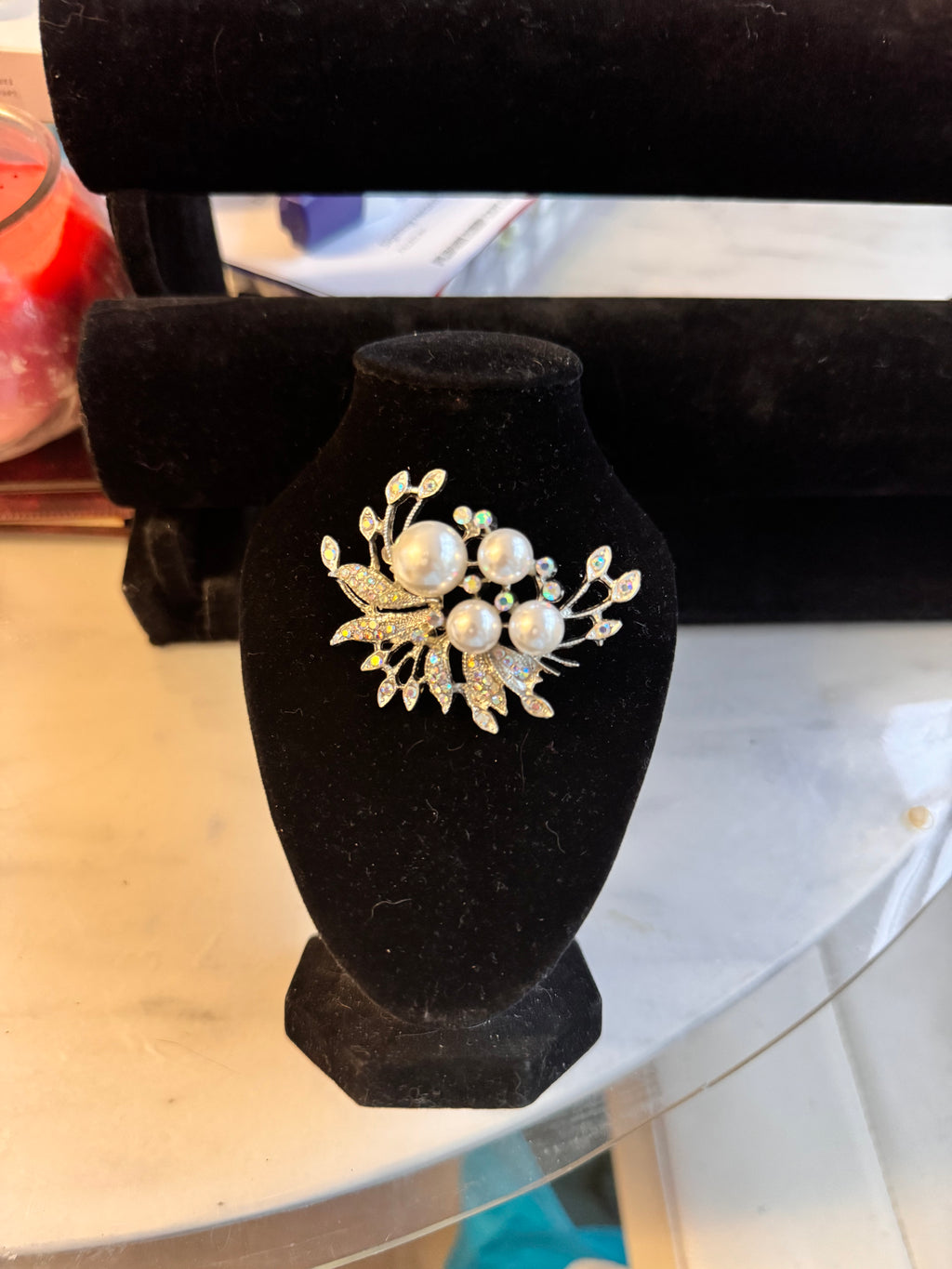 The silver tone version on a black bust and stood on a marble table. It features faux pearls and aurelia borealis rhinestones