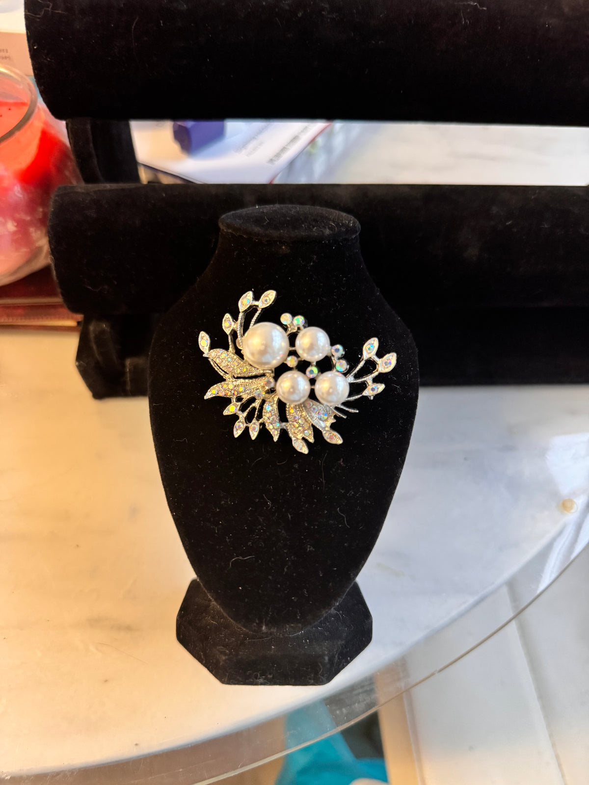 The silver tone version on a black bust and stood on a marble table. It features faux pearls and aurelia borealis rhinestones