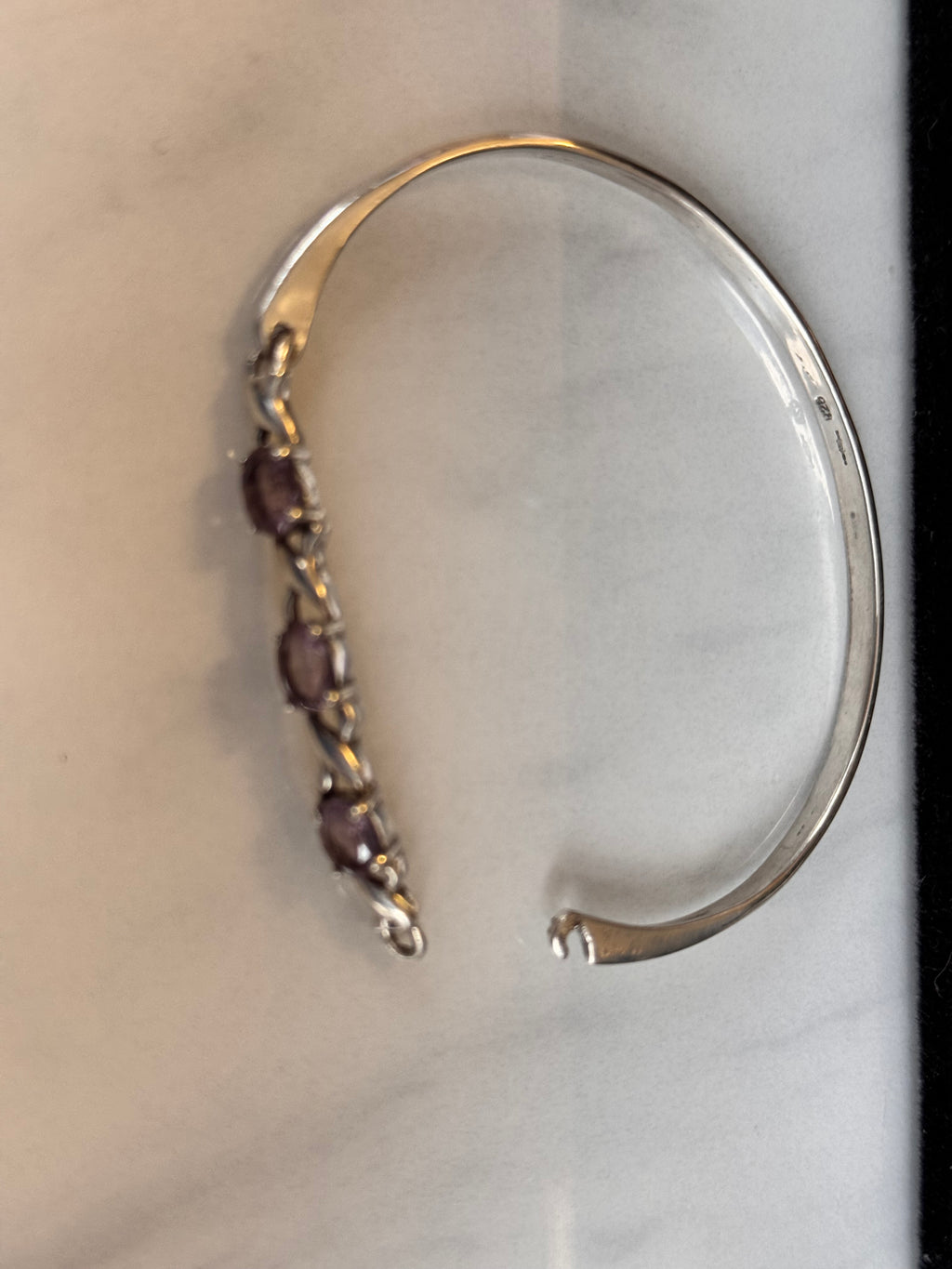 This image shows the opening and closure of the bracelet. it a squeeze and hook type then looks like an oval bangle when closed. You can see the hallmarks in this pic.