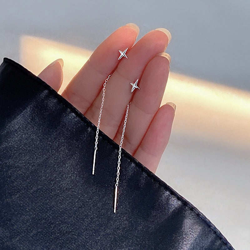 This image displays the silver-tone tassel earrings in a persons fingers