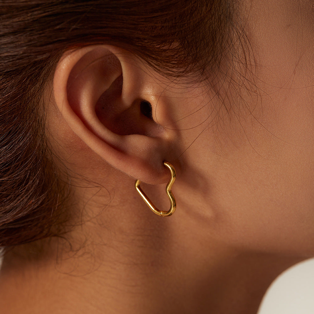 This image displays the golden heart hoops on an ear with the point of the heart at the back.