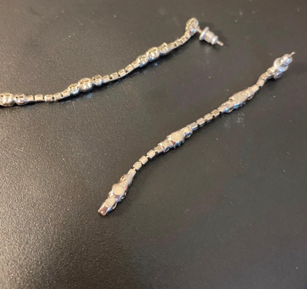 A silver-toned diamonte  earrings with a textured, beaded chain and these would go lovely with the matching bow riviera necklace. Displayed on a dark gray surface.