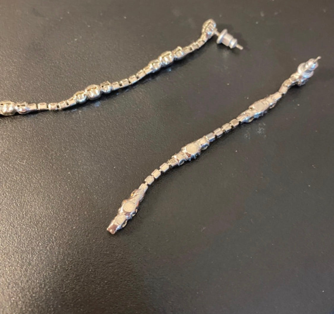 A silver-toned diamonte  earrings with a textured, beaded chain and these would go lovely with the matching bow riviera necklace. Displayed on a dark gray surface.