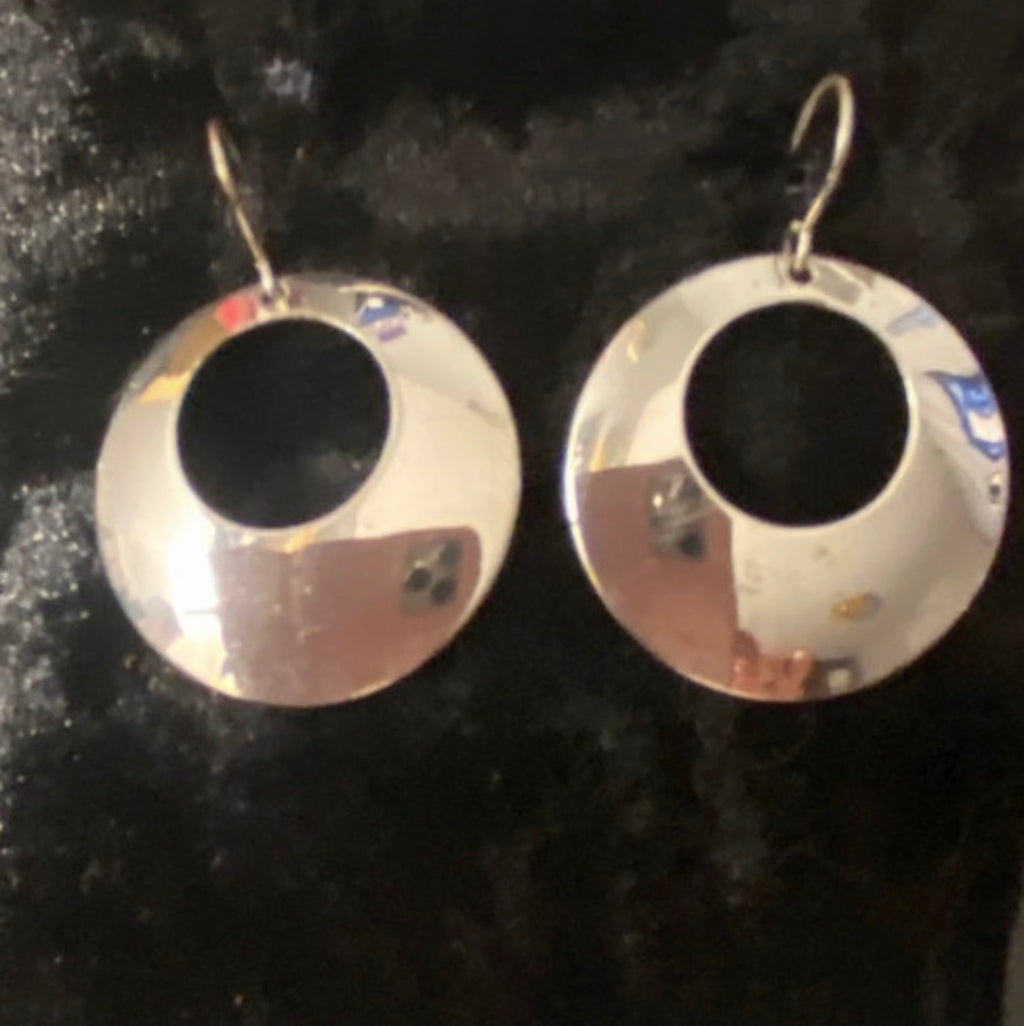 Close up of silver plated circle earrings with a hole on fish hooks. They have a mirror finish and and are elegant earrings in good condition