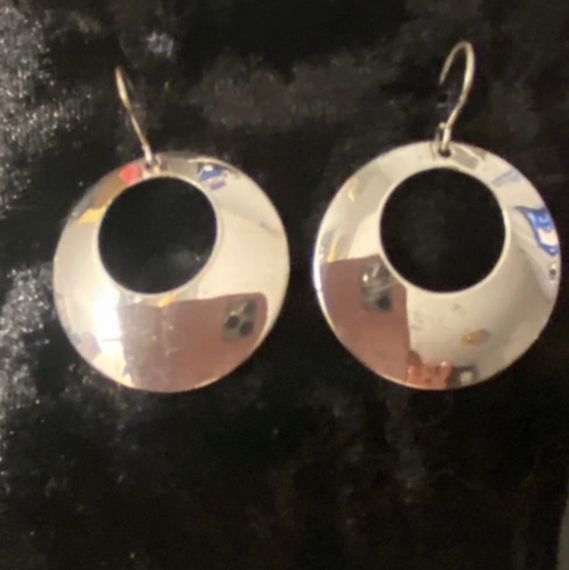Close up of silver plated circle earrings with a hole on fish hooks. They have a mirror finish and and are elegant earrings in good condition