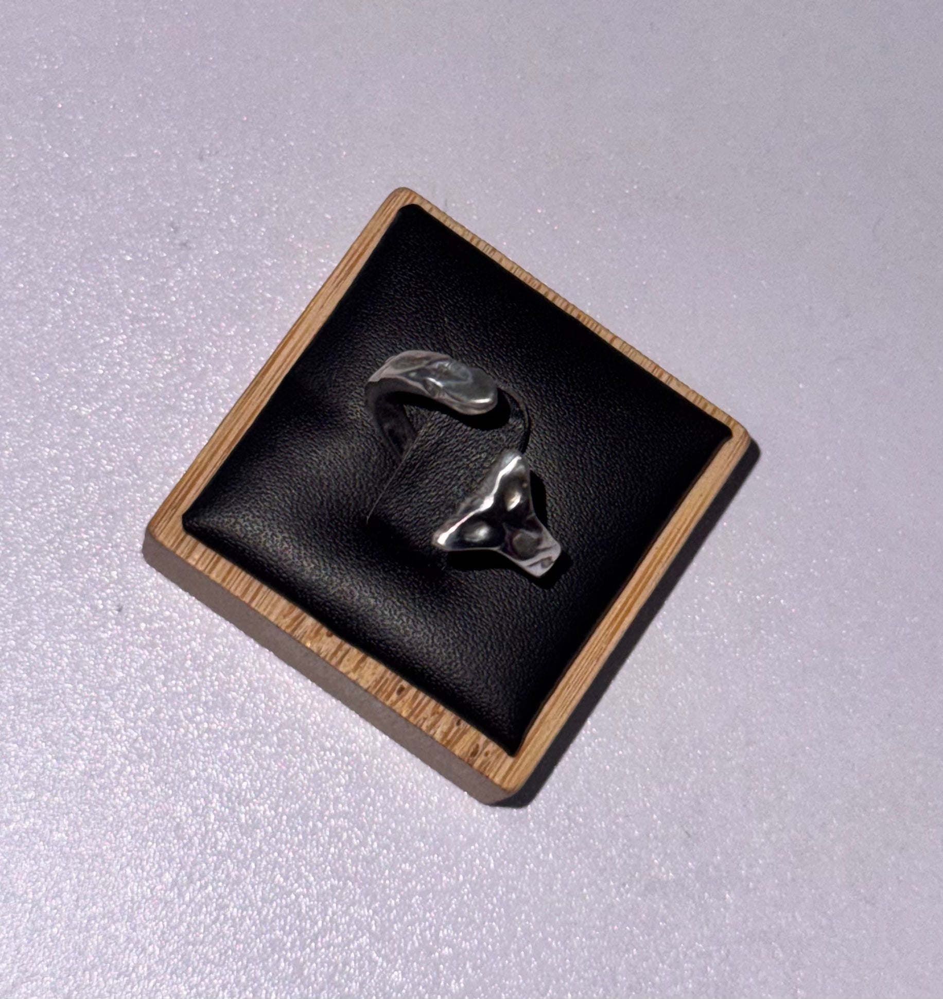 A sterling silver s925 silver snake ring displayed on a black textured ring pad inside a square wooden presentation box, set against a light gray background.