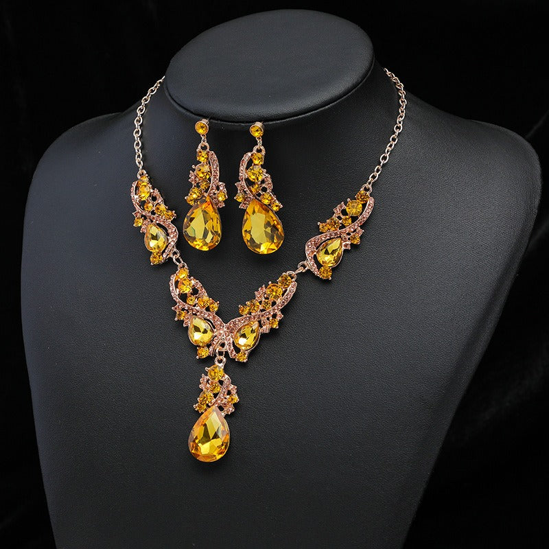 The yellow faux Citrine jewellery set on Gold-tone metal. Vintage style statement necklace and earrings with Citrine coloured faux gemstones on a charcoal bust.