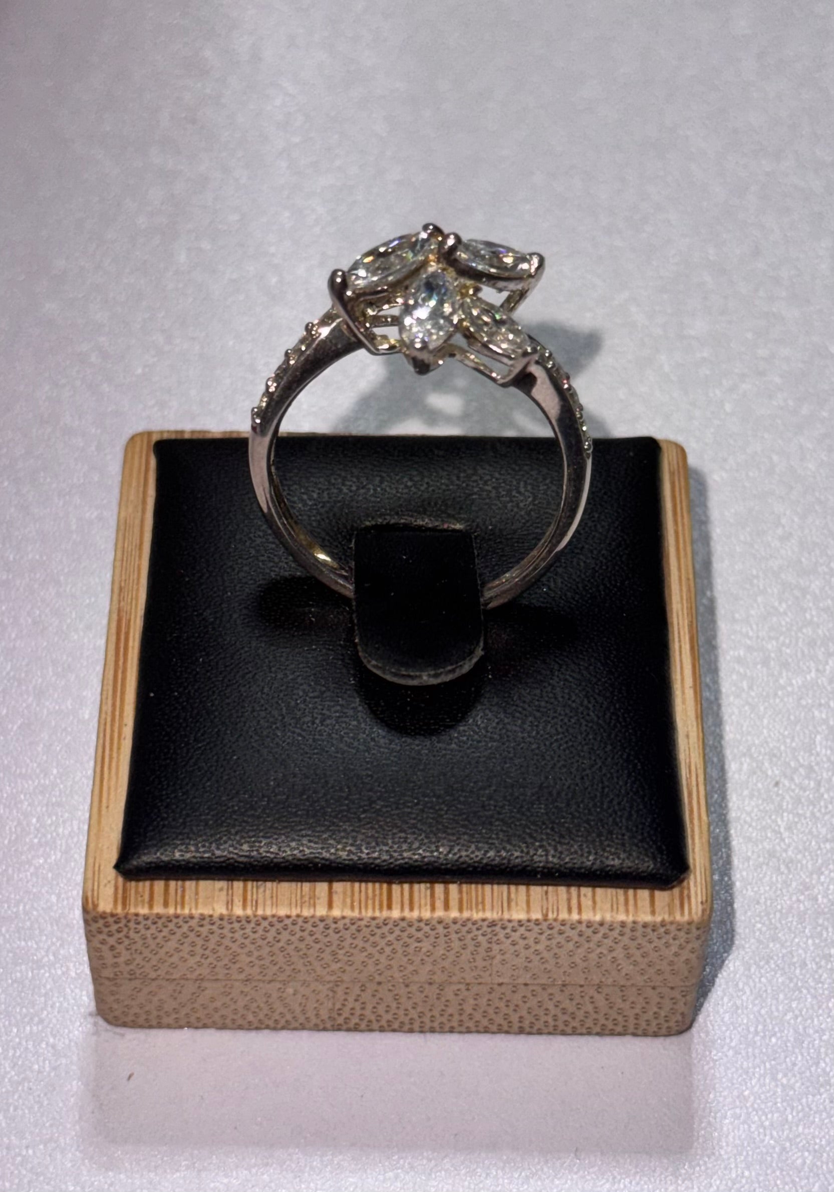 Another angle of the sterling silver ring with a starburst -shaped crystal cluster setting, displayed on a black cushion inside a light wood box