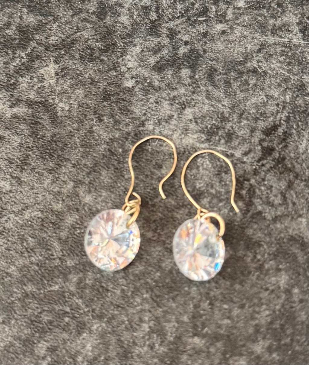A pair of 9ct Gold dangle earrings with round, faceted clear iridescent crystals, displayed on a textured gray background.
