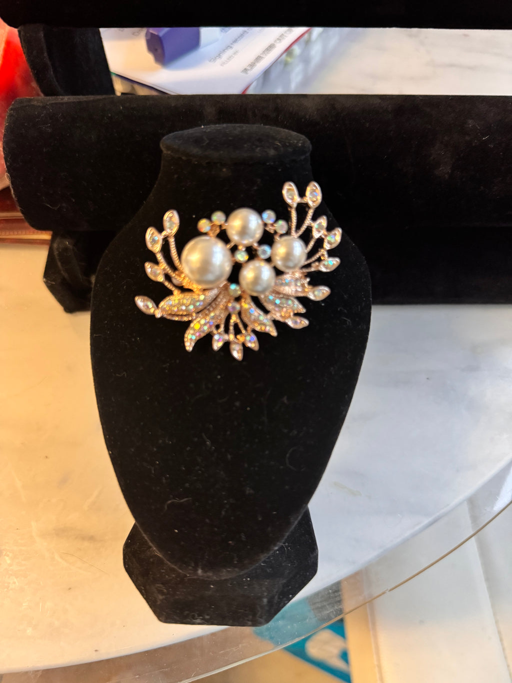 Gold tone Brooch with faux pearls and aurelia borealis rhinestones Very Vintage but brand new. On a Black bust and displayed on a marble table