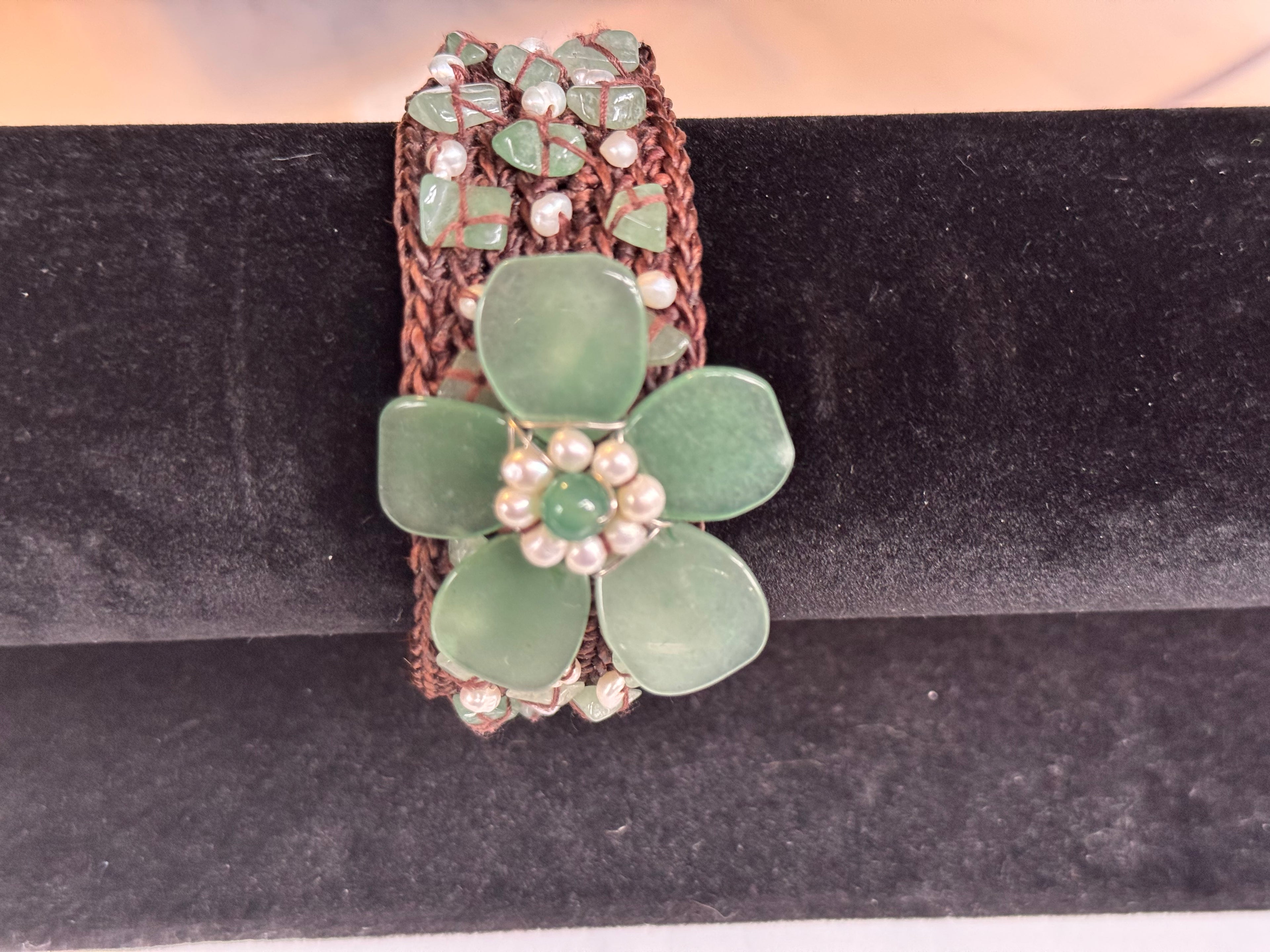 Close-up of large carved green jade flower on vintage woven bracelet