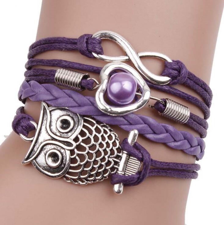 Purple Owl multilayer friendship type wider bracelet. has an eternity charm, owl and a heart & bead across 4 differing strands. The strand next to the owl is plain and plaited