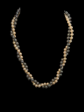 A double-strand pearl necklace featuring alternating strands of cream/off-white and dark gray pearls, displayed against a solid black background.