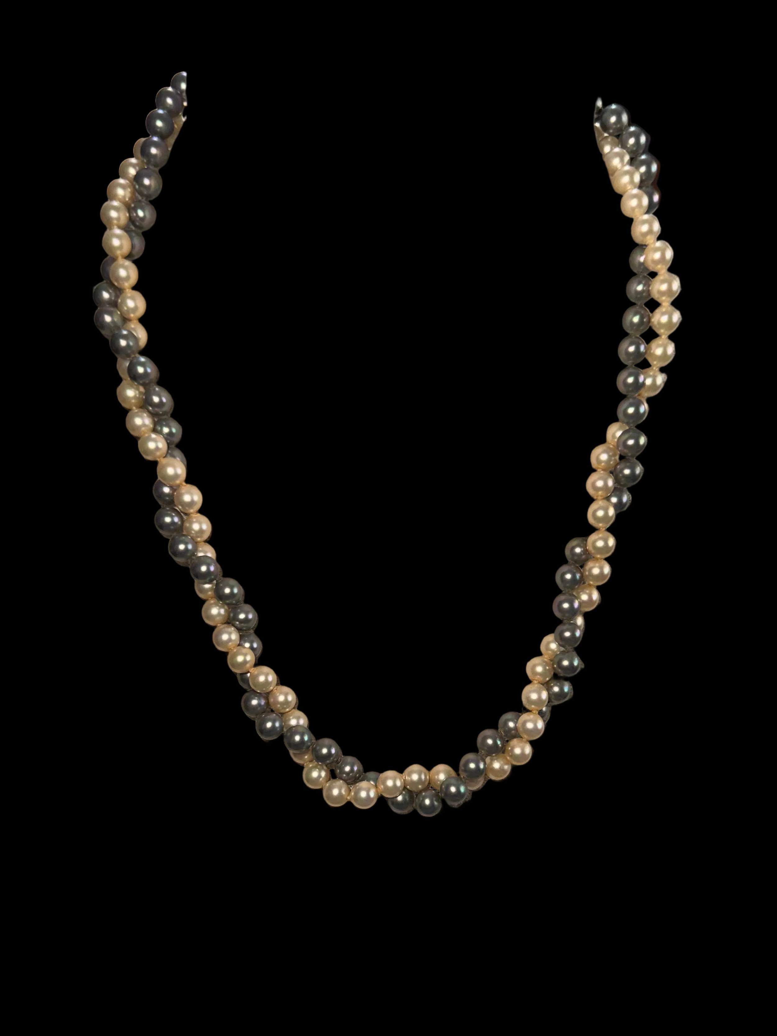 A double-strand pearl necklace featuring alternating strands of cream/off-white and dark gray pearls, displayed against a solid black background.