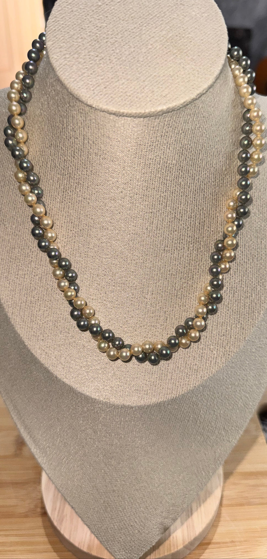 A double-strand beaded necklace with alternating dark gray and light beige pearls, displayed on a beige fabric jewelry bust. Faux Pearls in Grey & cream English Rose
