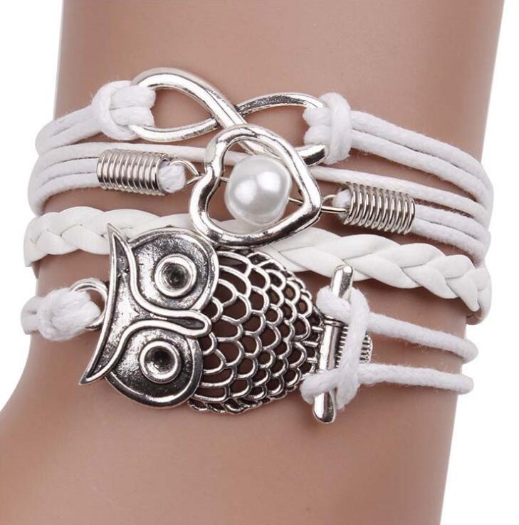 White Owl multilayer friendship type wider bracelet. has an eternity charm, owl and a heart & bead across 4 differing strands. The strand next to the owl is plain and plaited