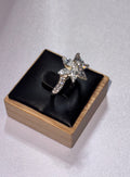 A sterling silver star-shaped ring set with clear crystals, displayed on a black cushion inside a light wood jewelry box against a light gray background. Size Q 1/2