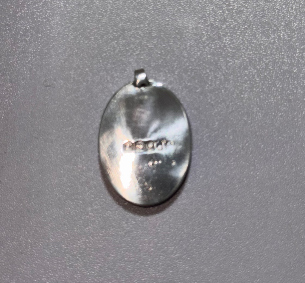A 2cm length oval sterling silver pendant with a bail at the top, photographed on a textured gray background. Displaying the original hallmark