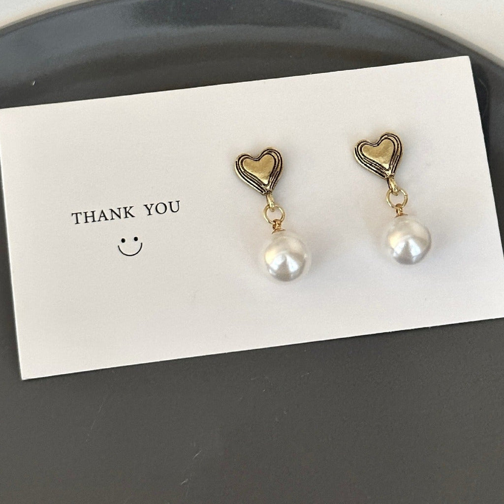 Heart Earrings and faux pearl on a white card saying Thank you with a smiley face