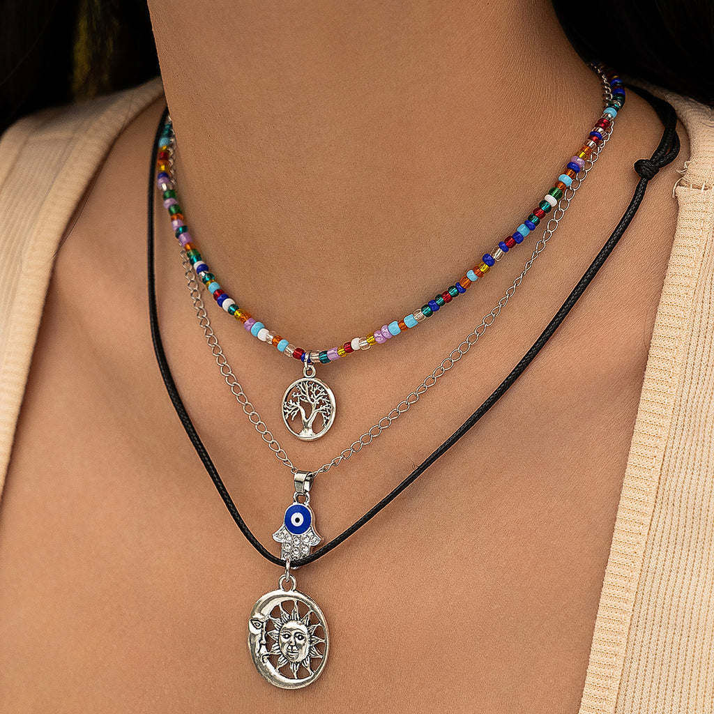 This pendant is more multi coloured with blue navy mid brown and white beads with a tree of life pendant. the next is a chain with hand and blue & white eye in a round shape. the third has a sun and moon pendant. one bead one chain and one cord.