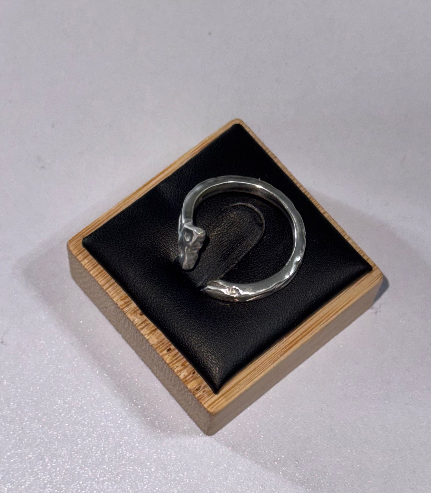 The sterling silver sea snake ring on its side to display the ring from a different angle. its laid on a ring display box.