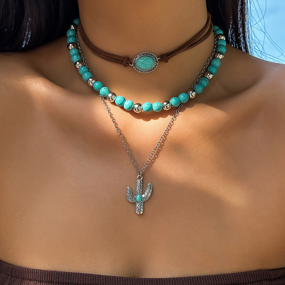 This style is a choker with a larger bezel set turquoise coloured semi precious stone or turquoise Howgate. Then a layer of turquoise and silver tone round beads and a silver tone Chain with is longer with the Cactus which also has a central turquoise stone.