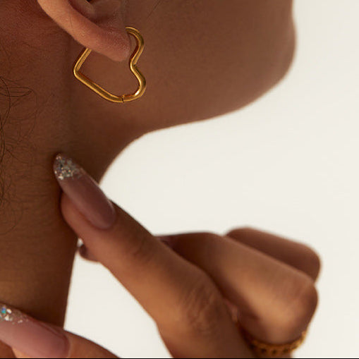 The Gold Tone Sleeper in an Ear & beautiful nails pointing to them. On a white background.